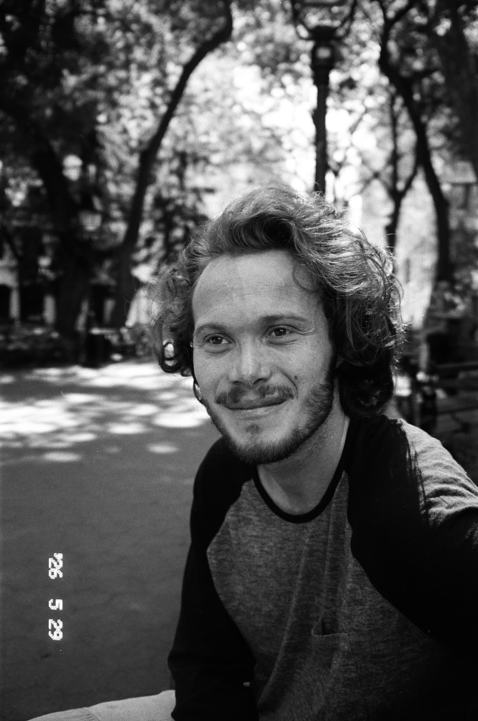 Black and white portrait of Ethan smiling in a park