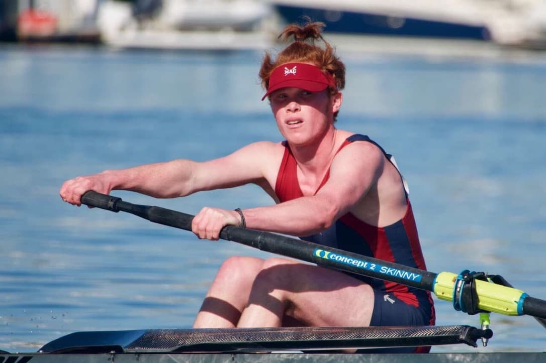 Ethan rowing in a single scull, mid-stroke