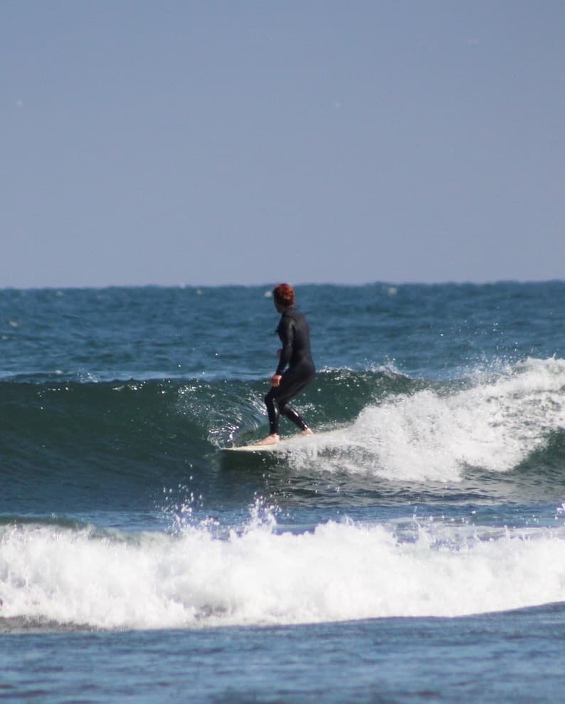 Ethan standing balanced on a surfboard riding a wave